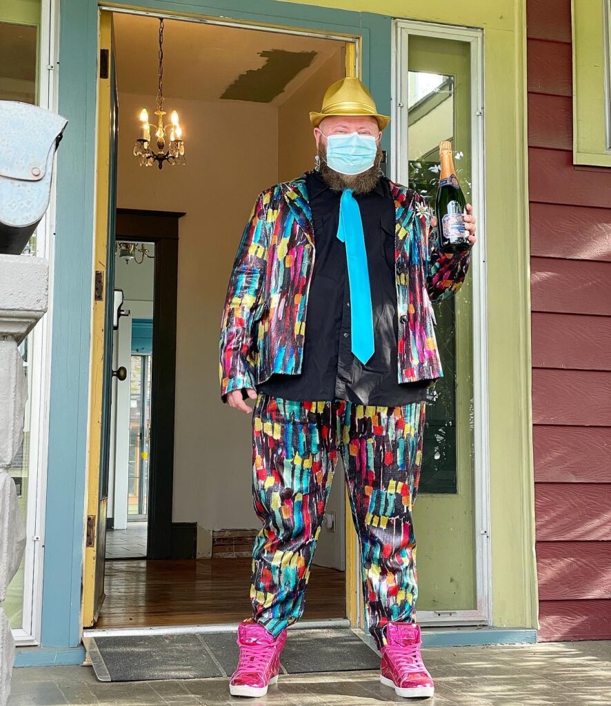 Chaz wearing the most fabulous outfit accompanied by a fancy champagne bottle in front of his new house on Keys Day™️