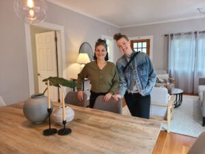 Bonnie Roseman and Trish Sunderland, Realtors at Living Room Realty stand smiling in a staged dining/living room.